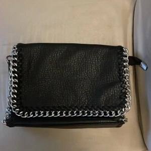 Äkta TIAMO M - Svart TIAMO i storlek M. Väskan är nyskick med ett fack på utsidan samt tre minsta på insidan. 