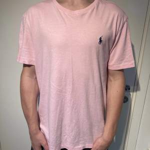 Ralph lauren T-shirt i rosa, 9/10 skick knappt använd dock en liten tråd lös längst ner på framsidan, orginalpris 699kr. Modellen är 171 