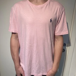 Ralph lauren tshirt - Ralph lauren T-shirt i rosa, 9/10 skick knappt använd dock en liten tråd lös längst ner på framsidan, orginalpris 699kr. Modellen är 171 