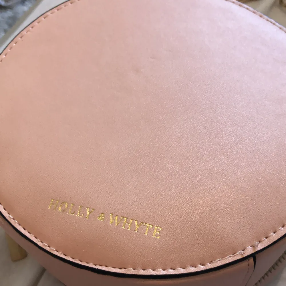 En liten rosa handväska från Holly & White i bra skick som inte har kommit till användning . Väskor.