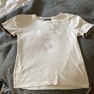 Vit t-shirt  - Säljer denna jättesnygga t-shirt med guld detaljer på ärmarna🤎