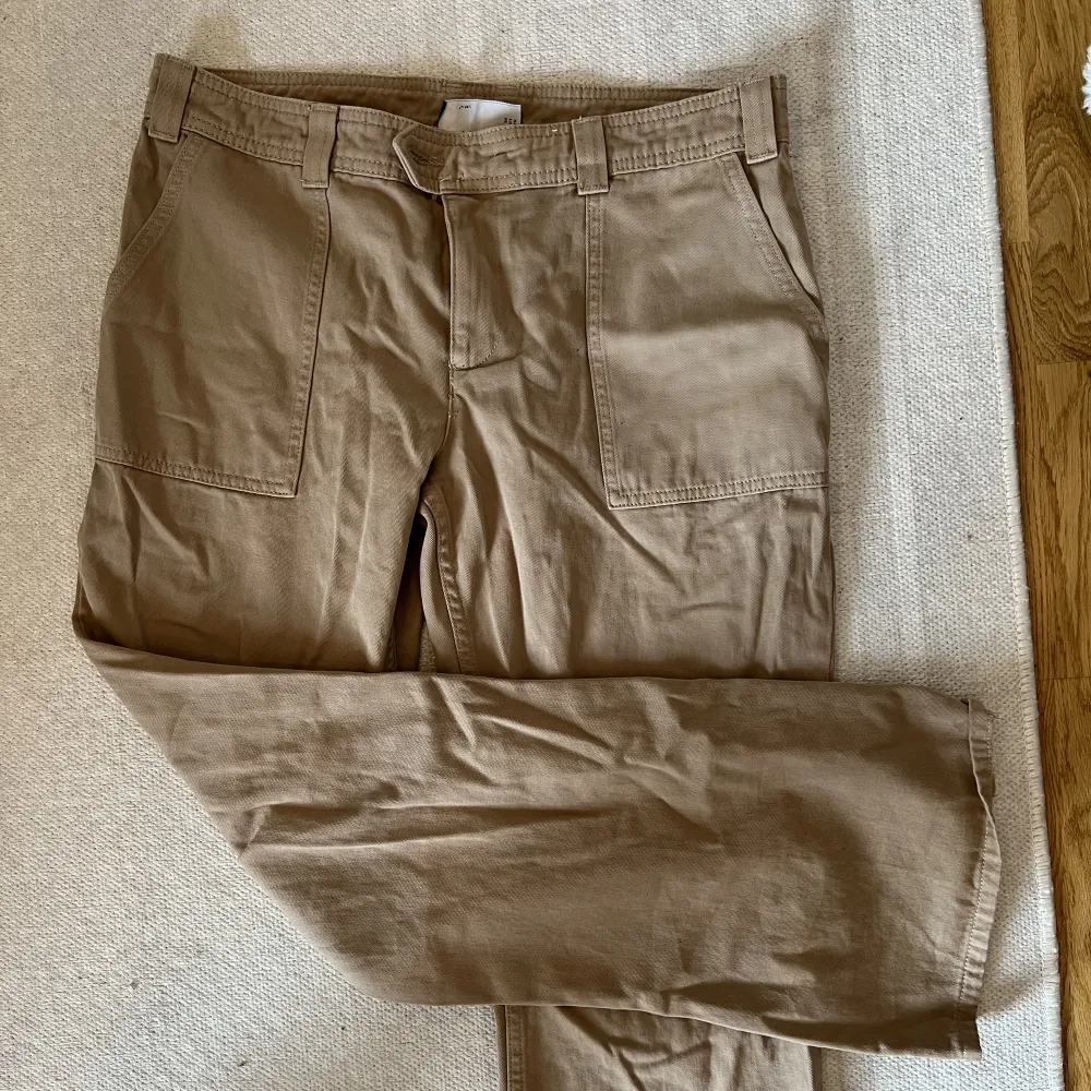 Snygga och coola beiga kostymbyxor i jeansmaterial, i low waist modell från ASOS. Passar till mycket och går att både klä upp och klä ner. Dessa är köpta i storlek 40 för att få en mer baggy look. . Jeans & Byxor.