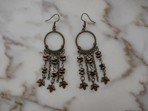 Oanvända örhängen  - Oanvända örhängen i någon mässingsfärgad metall och "stenar" av plast, tror jag. De är totalt nästan 9 cm långa. 