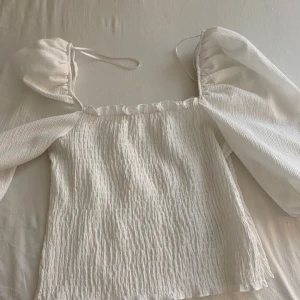 Vit sommrig topp med puffiga armar -  En vit sommrig topp med puffiga armar Den är i bra skick inte användt så många gånger 