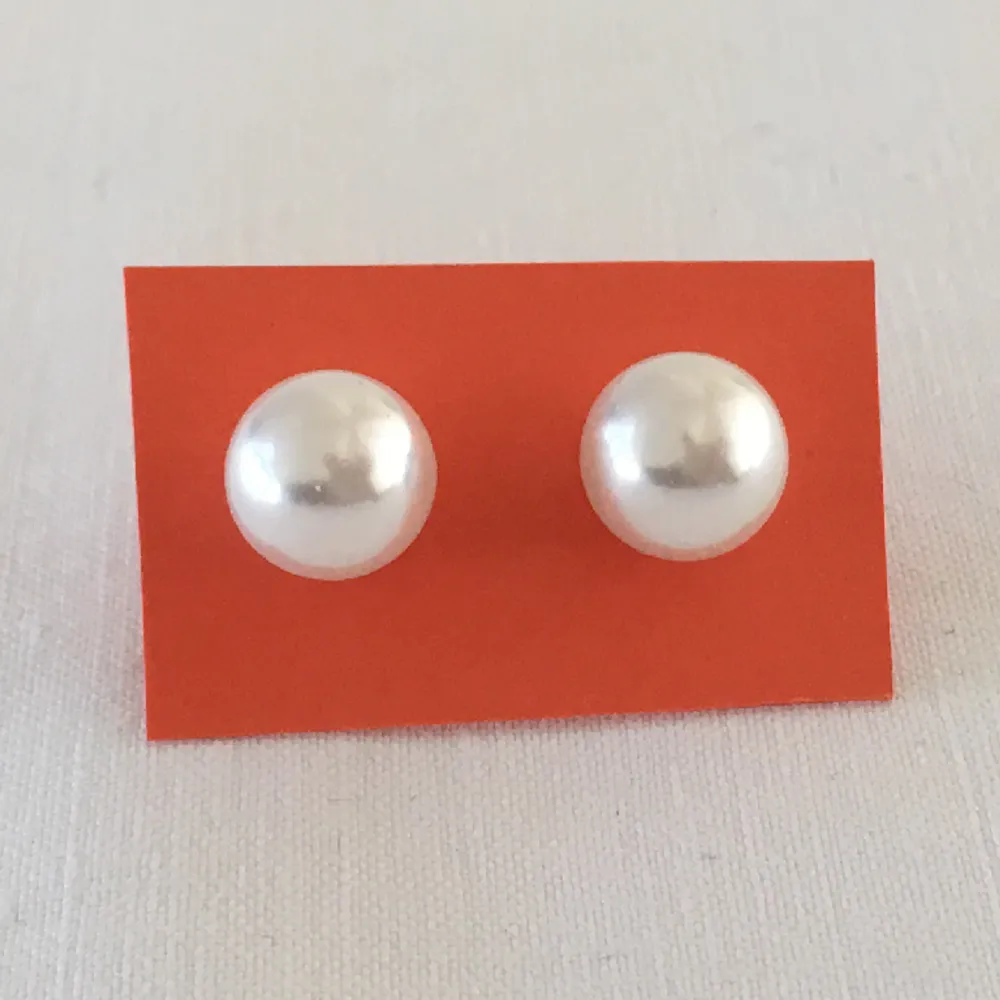 Örhängen med artificiell pärla, troligen i glas för den väger mer än om det vore plast. Jättefin yta i pärlemor. Pärlan är ca 1 cm i diameter. . Accessoarer.