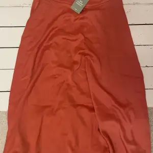 Vadlång orangeröd kjol, tyvärr inte kommit till användning så helt ny med prislapp, originalpris är 349kr.