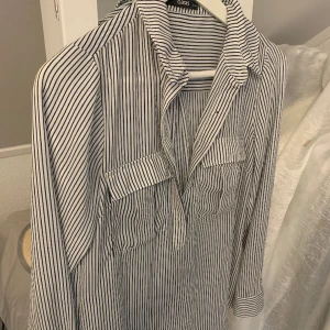 Randig skjorta - Elegant, randig skjorta. Tyget är aningen tungt så sitter snyggt på. Mörkblåa ränder. 