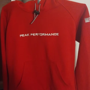 Huvtröja Peak Performance  - En jätte fin tröja i väldigt bra skick då den bara använts två gånger. Den kommer inte till användning hos mig då rött är en färg jag tyvärr ser hemsk ut i. Insidan och snöret på tröjan är i ljusgrått. Storlek medium men inte en stor medium enligt mig. 