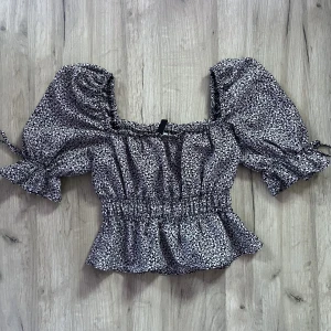 Blommig top - En somrig top med resår i ärmarna och i midjan. Den är lite tajtare i ärmarna så det är därför jag säljer den. Men jag har vanligt vis S i storleken så om man har S kan man säkert ha den.