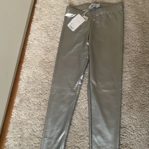 Silvriga tights  - Jättecoola silvriga tights i storlek 158/164. Helt oanvända, lappen kvar. Originalpriset var 130, säljer för 60. Hör av dig om du är intresserad eller har frågor!