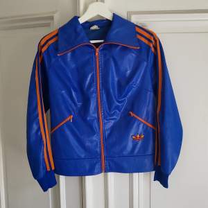 En blå och orange vintage adidas jacka i bra skick. Luftig och perfekt för sommaren
