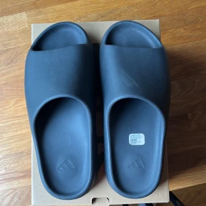 Yeezy Slide onyx  - Säljer mina yeezy slide onyx st 47 passar 45-46. Skick 9/10 andvända 3-5 gånger. Original box med och kvitto. Skriv till mig vid mer frågor.