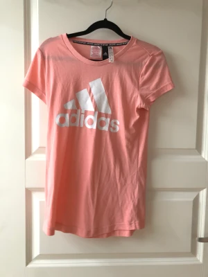 Adidas Rosa T-shirt - Säljer denna rosa t-shortsen som aldrig är använd och är nyskick, hör av dig för fler bilder och information