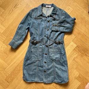 En kort jeans klänning från Chloé med knappar, inbyggt bälte och 7/8 ärm. En svensk 38.