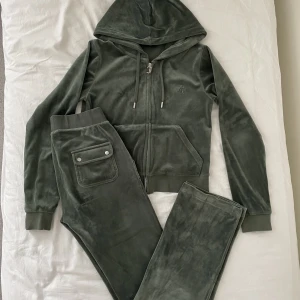 Juicy Couture Velour Del Ray Tracksuit - Säljer nu mitt älskade Juicy Set i färgen ”Dark Moss” som köptes förra hösten och inte längre finns kvar att köpa på hemsidan! En av metallslutningarna på byxornas snören är borta men annars är setet i bra skick!  Byxor: S Zip-up: M (passar S & M)💚
