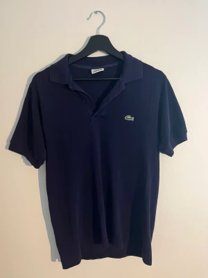 Lacoste piké - En mörkblå piké tröja frön lacoste. Den är inte jätte använd. Saknar knapp men går att fixa. Kan postas och mötas upp. Betalningar sker via swish!