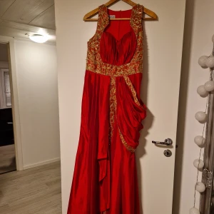 Röd balklänning  - Röd långklänning med gulddetaljer. Sparsamt använd. Strl M/L.