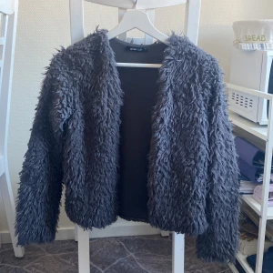 Lurvig kofta utan knappar - Grå, lurvig kofta från Gina Tricot. Inte jättetjock men man blir varm, går att ha som jacka under sommaren. Passar XS-M skulle jag säga.