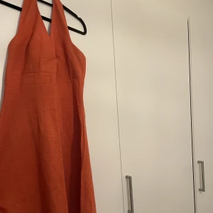 Halterneck orange klänning  - Jättefin orange halterneck klänning. Går nedanför knät. Tyget är lite grövre vilket gör att den faller fint. 