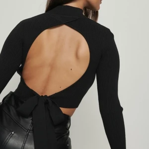 Svart polotröja med öppen rygg - Storlek M men sitter åt med ett väldigt stretchigt material. Tröjan är från NAKD.  Svart och ribbad.