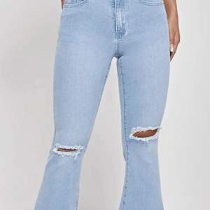 Ett par blåa utsvängda jeans med små hål. Helt nytt skick,super fina och sitter perfekt 
