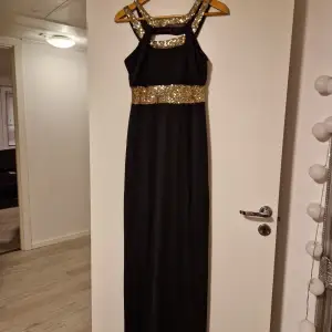 Superfin helt ny långklänning som jag säljer då den inte kommer till användning. klänningen är svart med guldpaljetter som är perfekt till balen. Strl L.