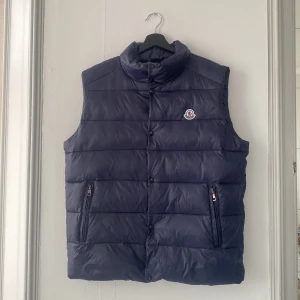 Moncler väst - Västen köptes begagnad och säljes nu pga fel storlek. Använd ett fåtal gånger av förra ägaren men är i nytt skick. Vid seriöst intresse kontakta mig gärna för fler bilder.😊 Ps. Frakten ingår ej i priset