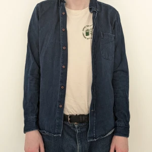 Jeansskjorta, These Glory Days - Jeanskjorta från These Glory Days. Översta knappen är halv och därför svårknäppt samt att färgen bleknat vid armbågarna, syns dock inte lika väl i person. 