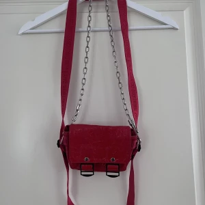 Zadig & Voltaire väska - Säljer min unika väska från Zadig & Voltaire. Väskan har två band där det röda är avtagbart. Har en liten fläck på baksidan precis ovanför märket (se bild). Den är av mindre storlek och perfekt när man inte bär med sig så mycket. Har fler bilder. 