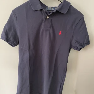 Ralph lauren  - Jag säljer en Ralph lauren piké, i mörkblå färg, storleken sitter som M/ S  den är i bra skick använd några gånger. Kontakta gärna för fler bilder eller funderingar!