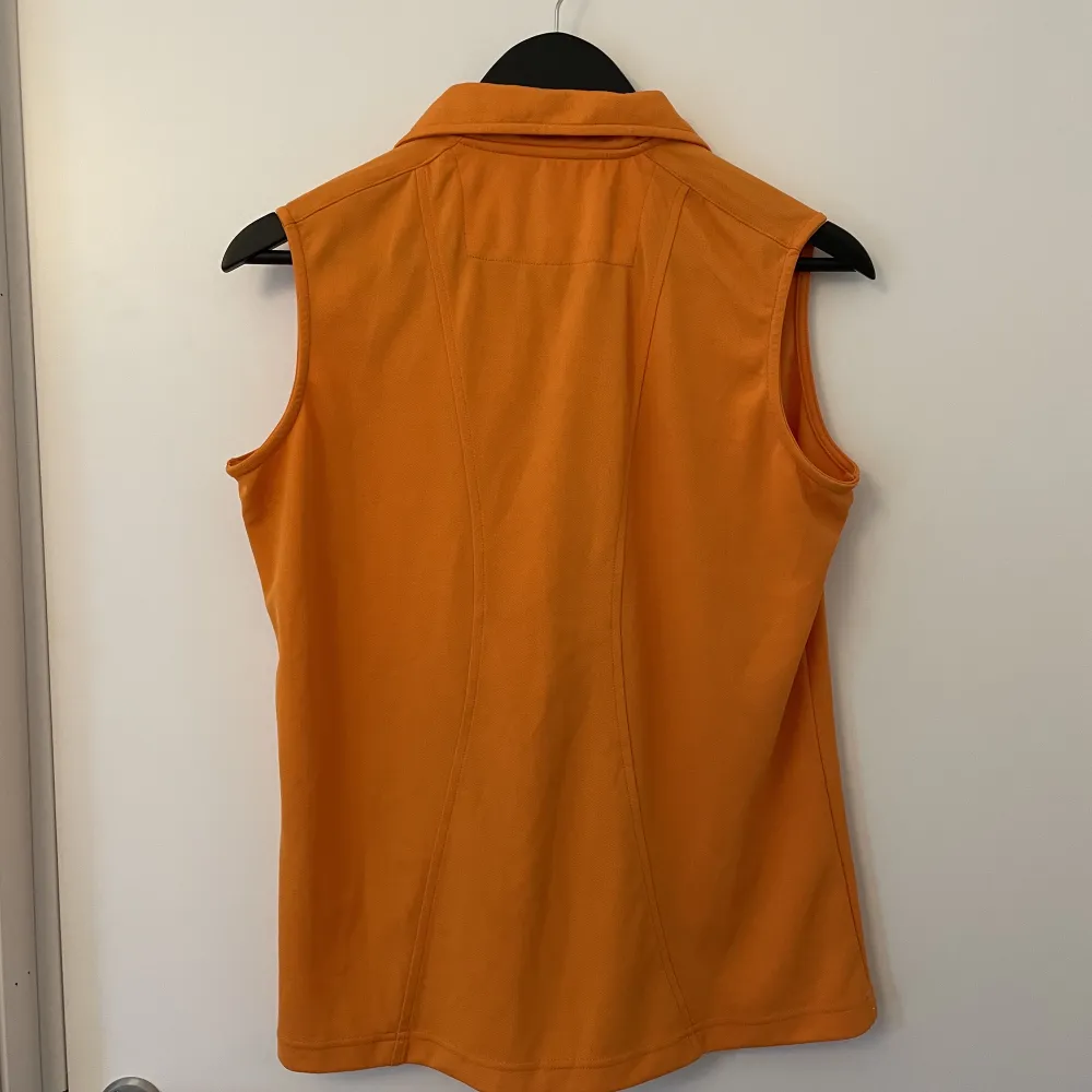 En orange pikétopp i träningsmaterial. Storlek XL men känns snarare som M-L. Toppar.