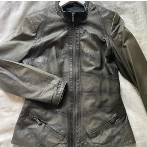 Skinnjacka - Supersnygg skinnjacka i en lite washed mörkgrön färg, jag tror inte att den är i äkta läder. Den är i mycket bra skick och sitter lite fitted, det står ingen storlek men jag tror att den är en strl S eller M då den passar mig som vanligtvis bär S