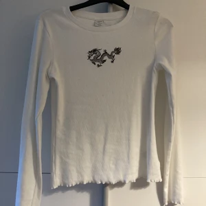 Tröja med drake  - Vit tröja från Lindex med en drake. Storlek 158/164 så ungefär xs men väldigt stretchig så passar även s.