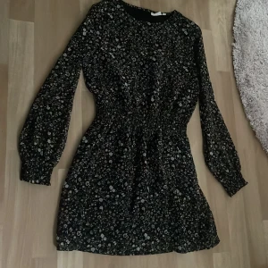 Kläning - En svart klänning med blommor på från kappahl. Använd några gånger men i fint skick.
