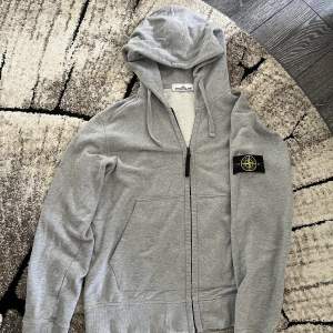 Begagnad stone island zip hoodie storlek M. Skick 7-8/10. Finns en liten defekt men det går att fixa. Varm och passar perfekt till vintern!