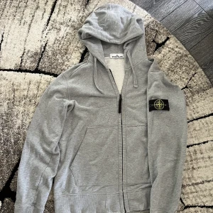 Stone island hoodie - Begagnad stone island zip hoodie storlek M. Skick 7-8/10. Finns en liten defekt men det går att fixa. Varm och passar perfekt till vintern!