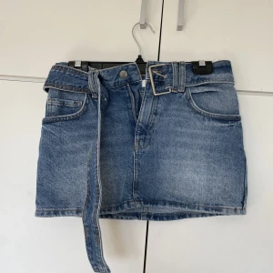 Lågmidjad Jeansekjol - Säljer denna ursnygga minijeansekjolen från pull and bear med tillhörande skärp. 