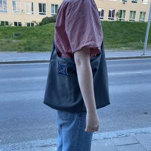 En handsydd väska gjord av återanvänt segondhand-tyg med fickor av Lars Wallin tyg❤️