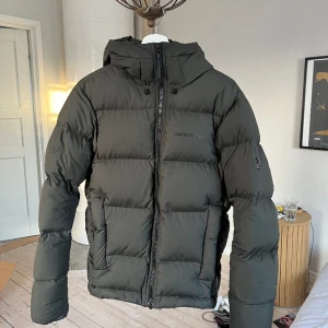 Peak Perfromance jacka - Säljer min ”rival” dunjacka från Peak perfromance som enbart är använd en vinter. Har ett väldigt litet hål som knappts syns (skriv för bild) annars väldigt fint skick. Supersnygg  mörkgrön färg som sticker ut lite från mängden.  Priset går att diskutera🤝