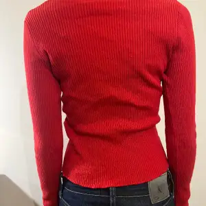 En röd tröja åt stickade hålet. Den är i bra skick använd fåtal gånger. Materialet är mellantjockt och lite räfflad.  Passar perfekt till hösten och vintern🫶 ställ gärna frågor eller be om fler bilder💕
