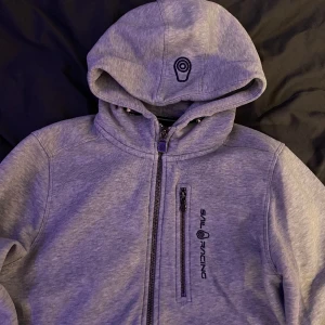 Sailracing kofta grå!🩶 - Hej! Jag säljer plagg jag knappt använder elr vad som. Denna sköna koftan är i bra skick och har ingen problem med dragkedjarna🩶 Den är i strl 170 o passar mig super!  Vid snabbt köp kan vi diskutera pris! Nypris- 1200kr