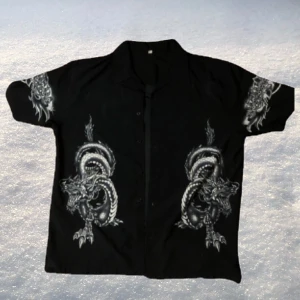 Vintage Skjorta med Drakmotiv - Vintage kortärmad skjorta med drakmotiv. Använd ett fåtal gånger men i bra skick. Supersnyggt tryck och sitter oversized. Skriv för mer bilder! Pris kan diskuteras…