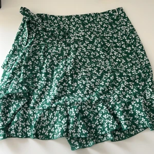 Kjol - Grön minikjol med dragkedja på sidan samt med en rosett som man dessvärre inte kan knyta åt 