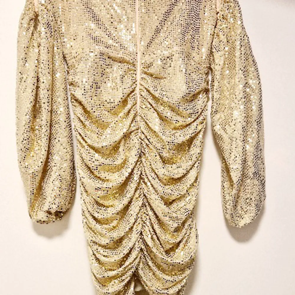 Champagne/Guld glittrig klänning med ärmar. Kort klänning, klänningen är rynkad baktill vilket ger en väldigt snygg kroppsfigur.  Använd 1 gång på min 30 årsfest. . Klänningar.