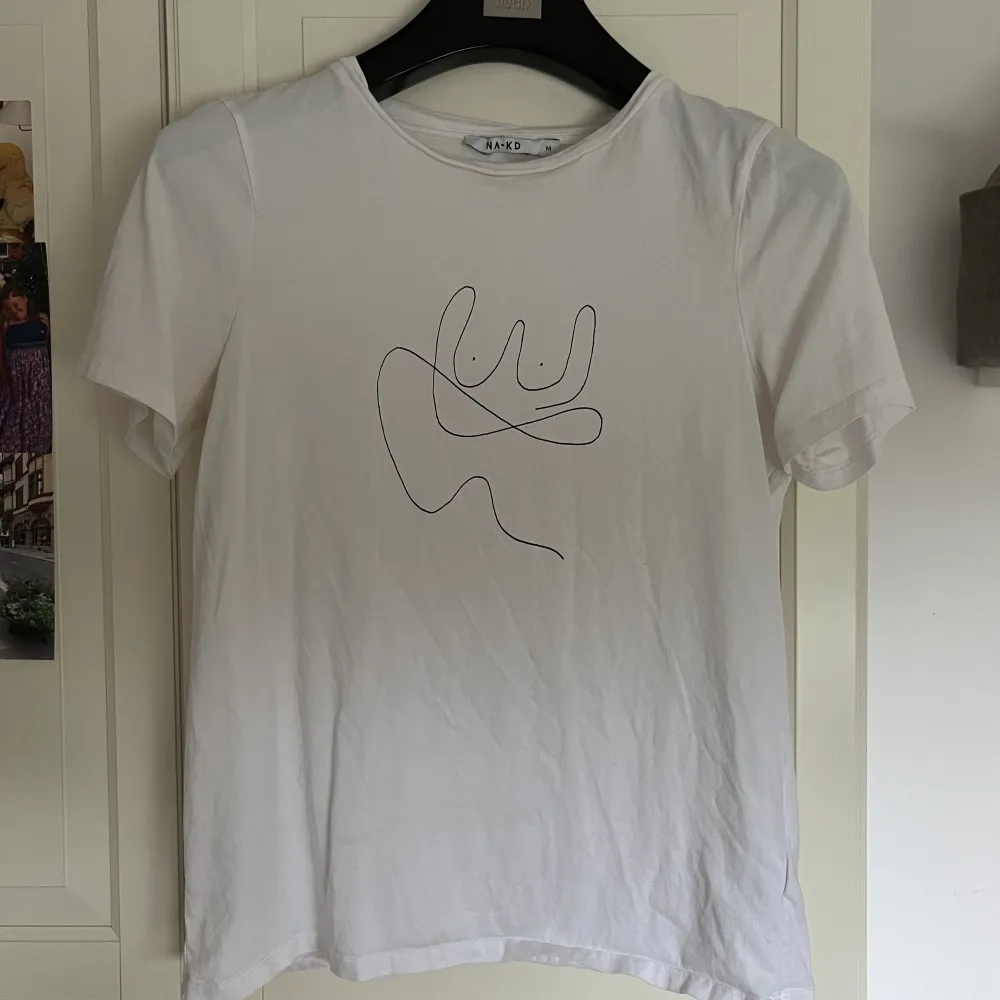 Snygg vit T-shirt med tryck från NAKD. Köpt för längesedand Säljer då den är för stor för mig.. T-shirts.