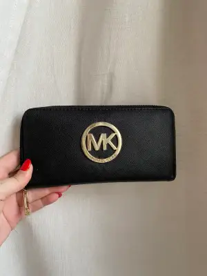 Plånbok från Michael Kors. Har hängt med ett tag så några små slitningar och dragkedjan till myntfacket är sönder. 