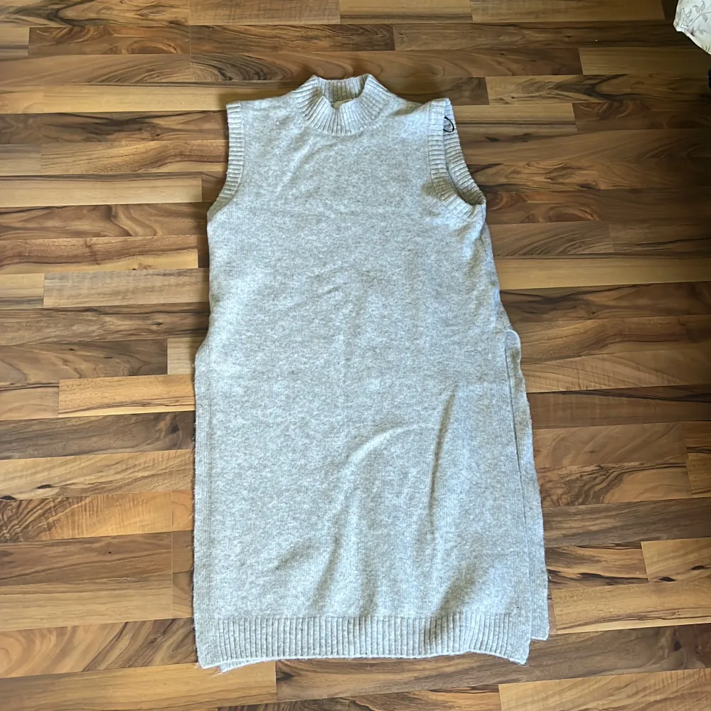 Beige, stickad tunika som går till ca knäna. Ganska tjockt material med lång hals samt långa slitsar på båda sidorna vilket gör den riktigt snygg. Helt oanvänd.. Neuleet.