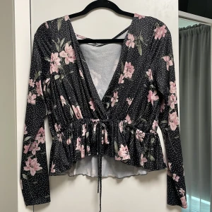 Peplum blus blommig - Peplum blus i blommig design och polyester i material. Den är blommig och har en liten band runt midjan där man kan justera själv hur tajt man vill ha den. Den är använd 2 gånger. Helt ny i skick. Storlek L