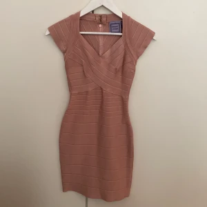 Hervé Léger bandage miniklänning - Klassisk miniklänning från Hervé Léger i en gammelrosa färg. Storlek XS/34. Använd en gång och i perfekt skick utöver en tråd som lossnat 2 cm, i princip osynligt och enkelt att laga, vänligen se bild. 