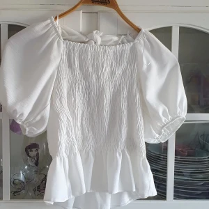 Vit topp med puffärm, strl 36 - Peplumtopp från new look i strl 36 med puffärm och snörning i ryggen!!! Supersöt till sommaren!!! i fint skick!🥰 